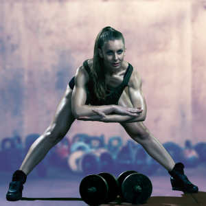 A fit, athletic woman stretching in a gym, demonstrating the flexibility and strength needed for peak performance and recovery.