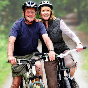 A happy and healthy senior couple with gray hair smiling while riding bicycles outdoors, embodying vitality and an active lifestyle supported by Vital Procollagen.